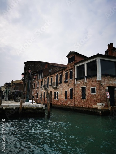 Venetian canal view featuring historic buildings and moored boats under an overcast sky