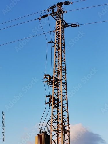 Electricity tower standing tall against a clear sky during the late afternoon hours