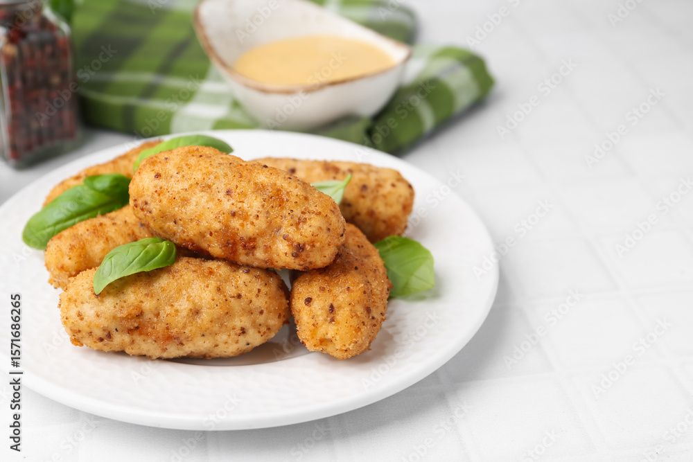 Tasty fried croquettes, basil and sauce on white tiled table, closeup. Space for text Tasty fried croquettes, basil and sauce on white tiled table, closeup. Space for text