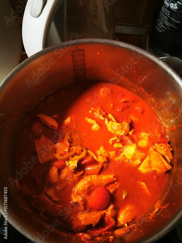 Delicious chicken curry simmering in a pot, blending spices and flavors in a home kitchen