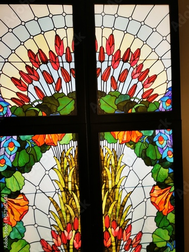 Colorful stained glass window featuring floral motifs in a well-lit interior space