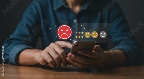 Person using smartphone to give a negative review with an angry face and stars on the screen display