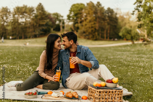 Valokuva Happy couple enjoying romantic picnic in park with juice and food
