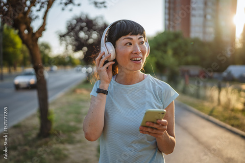 Wallpaper Mural Smiling japanese woman use cellphone while jogging on the street Torontodigital.ca