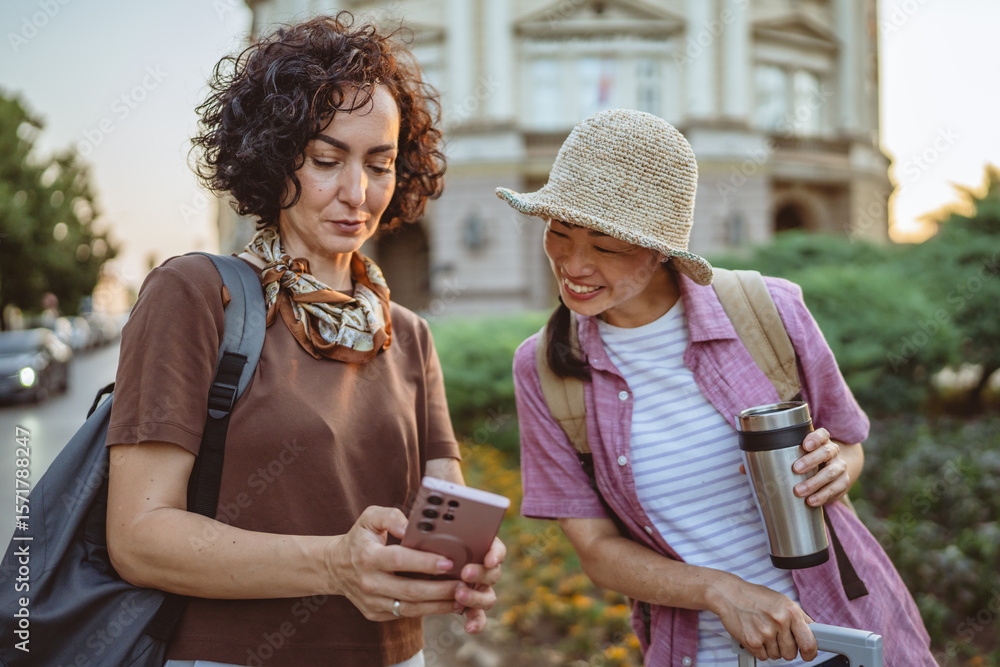 Fototapeta premium two women use mobile phone for directions walk and touring city