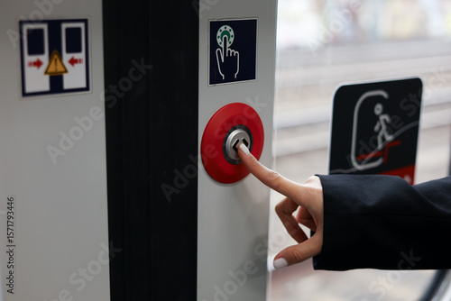 Close-up of girl's hand pressing green button of the train door to open it at the station. Female passenger waiting for train arrival and doors opening. Modern technologies in public transport