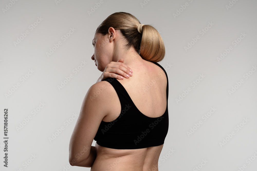 Naklejka premium Woman Experiencing Shoulder Pain with Visible Back View