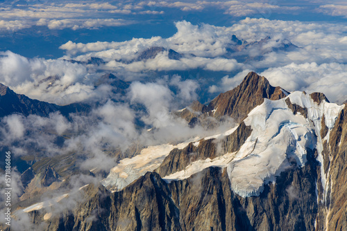 Mont Blanc ascent views on snow-covered ridge, surrounded by alpine peaks under clear and cloudy sky. High-altitude mountaineering, glacier terrain, mountain landscape outdoor expedition in Alps