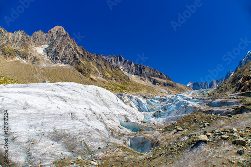 Glacier Argentiere in Chamonix valley, french Alps. Blue ice in a glacier serac and crevasse in the alpine scenic landscape in summer. Aiguille du Chardonnet mountain summit peak above the glacier