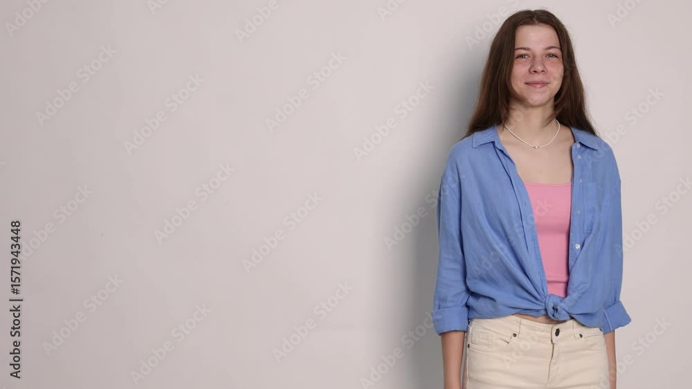 Teenage girl pointing at something on light grey background, space for text Teenage girl pointing at something on light grey background, space for text