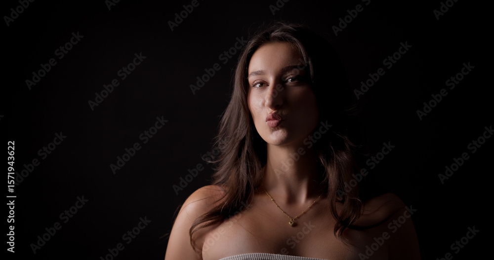 Studio portrait of a young woman puckering her lips on a black background Studio portrait of a young woman puckering her lips on a black background