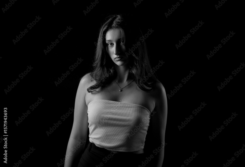 Naklejka premium Studio portrait of a young woman wearing a tube top and posing against a black background