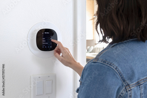 Adjusting the AC thermostat. Woman looking at smart thermostat menu