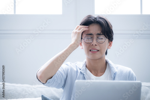 Man holding his head while looking at a computer A look of annoyance and distress A man holding his head after making a mistake or failure at work