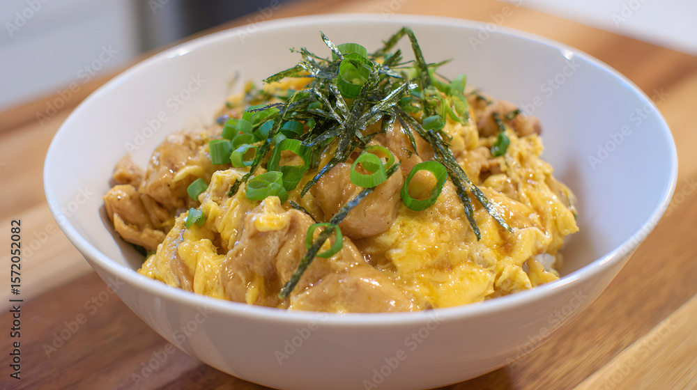 Delicious Oyakodon with Tender Chicken, Egg, Rice, and Green Onion Garnish in a Bowl Delicious Oyakodon with Tender Chicken, Egg, Rice, and Green Onion Garnish in a Bowl