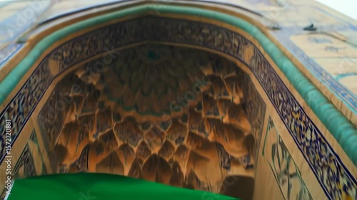 Iranian flag waving gently in front of a beautifully decorated building entrance
