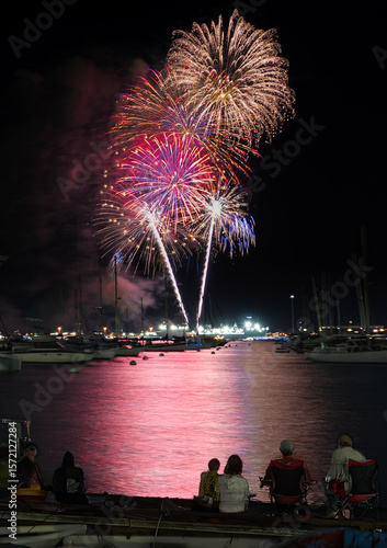 Fireworks seen by sitting people from boat docks 