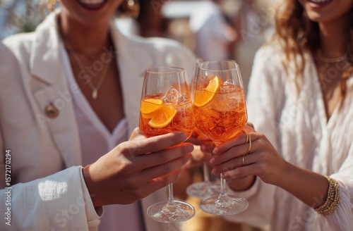 Close-up group toasting with orange cocktails in glasses, three professionals in white shirts against light beige background, warm sunlight for corporate hospitality advertising