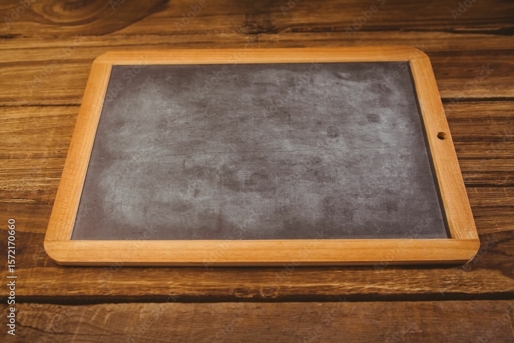 Fototapeta premium Blank rectangular chalkboard with wooden frame is lying flat on rustic wood table in flat design
