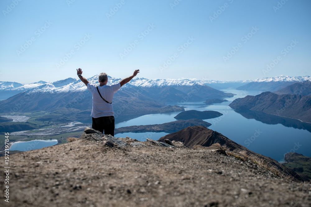 Obraz premium Rear view of hiking tourist making a heart symbol at the top of Roys Peak Wanaka New Zealand