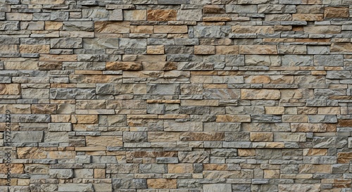 A textured wall of multisized natural stone blocks in shades of gray brown and beige creating a rugged pattern