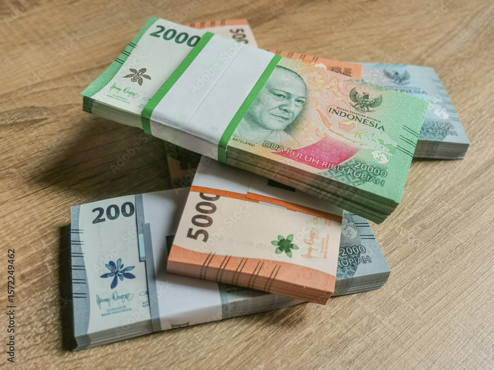Obraz premium Bundles of Indonesian Rupiah Banknotes on a wooden surface. Preparations for sharing good fortune during Eid al-Fitr.