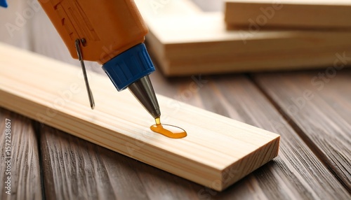 Glue gun applying hot melt to wood plank