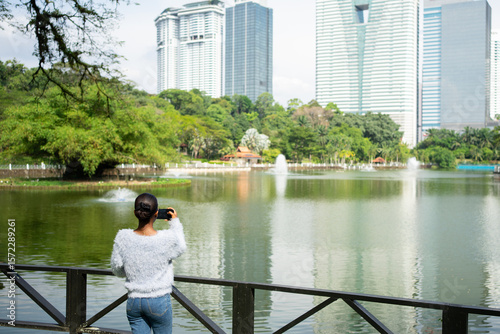 Photography Tourist taking pictures of lake and skyscrapers in kuala lumpur park
