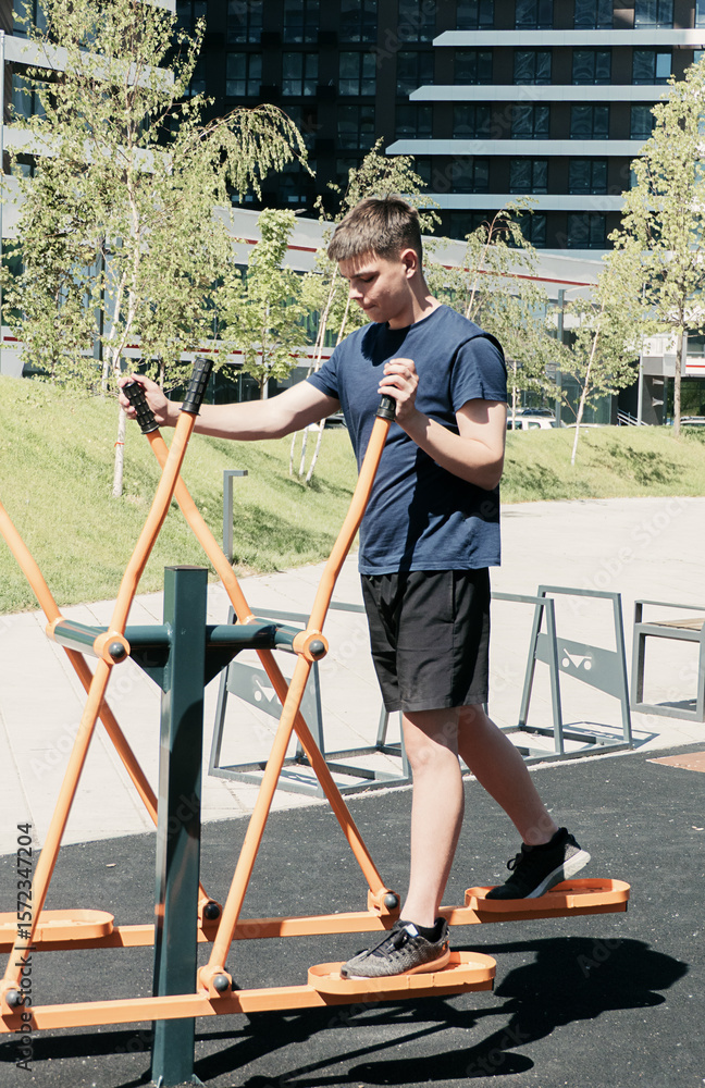 Φωτογραφία Young man exercising on an outdoor elliptical trainer in an urban park on a sunny day, focusing on fitness, health, and active lifestyle