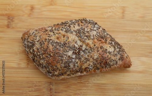 Bun sprinkled with anise seeds. On a wooden board.