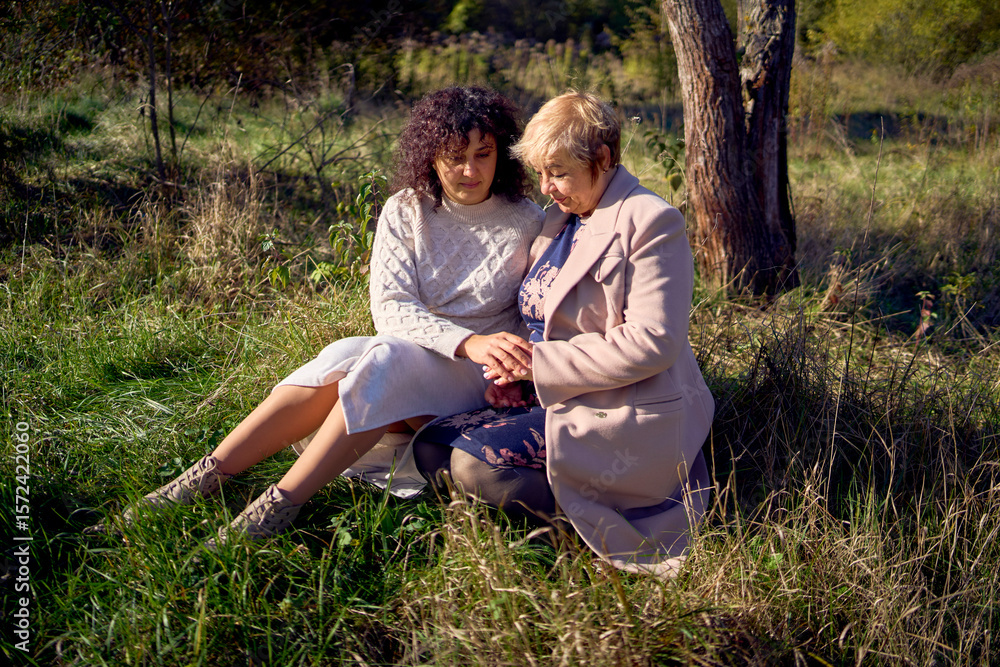 Fototapeta premium a middle-aged daughter and elderly mother together on a walk in the autumn forest