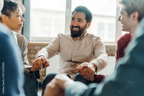 Fotografía Diverse teammates holding hands during office meeting