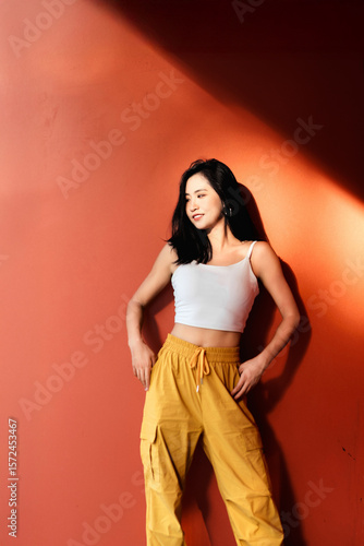 Fashionable and energetic sporty girl leaning against red wall