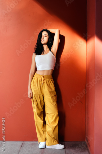 Fashionable and energetic sporty girl leaning against red wall