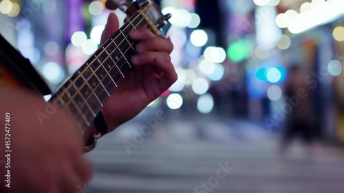 The image captures a close-up of a person's hand playing a ukulele. The fingers are gently pressing down on the strings, creating a sense of intimacy with the music being played.