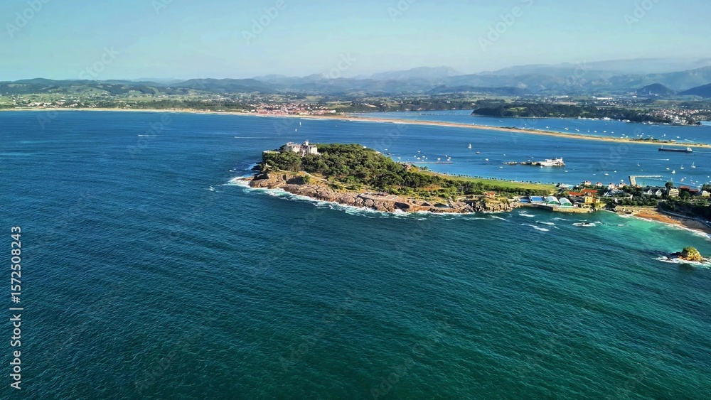 Fototapeta premium This aerial view captures a stunning coastal island surrounded by clear blue waters, creating a serene paradise