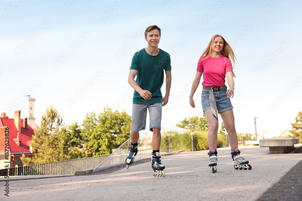 Fototapeta premium Happy couple roller skating together on street