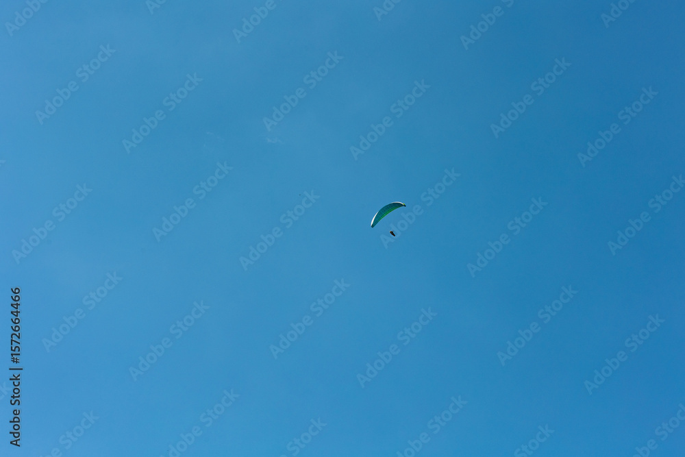 Paraglieder flies in the blue sky on a sunny day, Switzerland, Swiss Alps. Extreme sport, leisure activities, sunny day, outdoors, landscape. Paraglieder flies in the blue sky on a sunny day, Switzerland, Swiss Alps. Extreme sport, leisure activities, sunny day, outdoors, landscape.