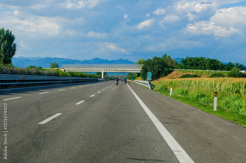 Fototapeta premium driving on the autostrada a21 toward brescia in northern italy during a sunny day with blue skies and clouds