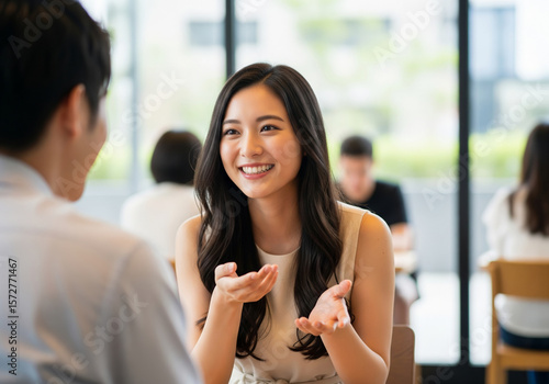 開放的なカフェでのデート、ベージュノースリーブワンピースを着たロングヘアの女性の心を奪う笑顔