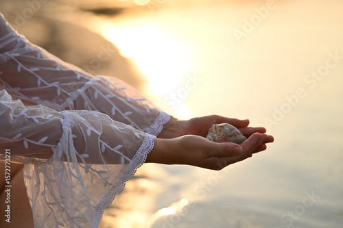 Φωτογραφία photo shoot of a woman in a white pareo and a black swimsuit at sunset on the be