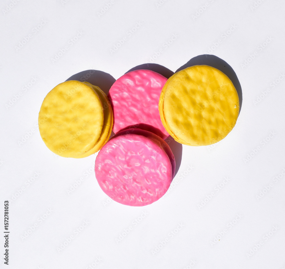 Naklejka premium Pink and yellow round glazed biscuits isolated on white background, top view