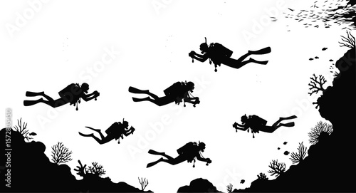 Silhouette of two scuba divers with cameras swimming underwater near coral and fish in the ocean water