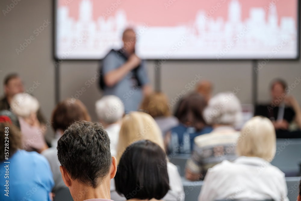 Obraz premium Unfocused view of an audience listening to a speaker during an educational event or presentation.