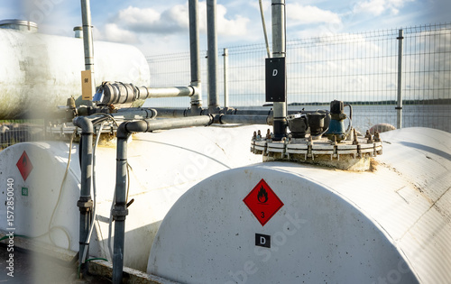 Industrial fuel storage tank with warning labels and piping system.