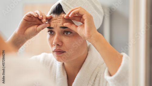 Canvas Print Woman looks in the mirror noticing the first wrinkles
