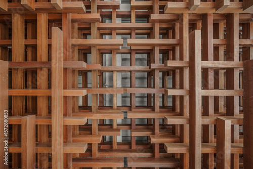 Abstract architectural detail of an interlocking wooden lattice. The 3D geometric structure creates a complex pattern of light and shadow. Modern design.