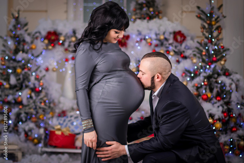 The husband kisses belly pregnant wife at Christmas