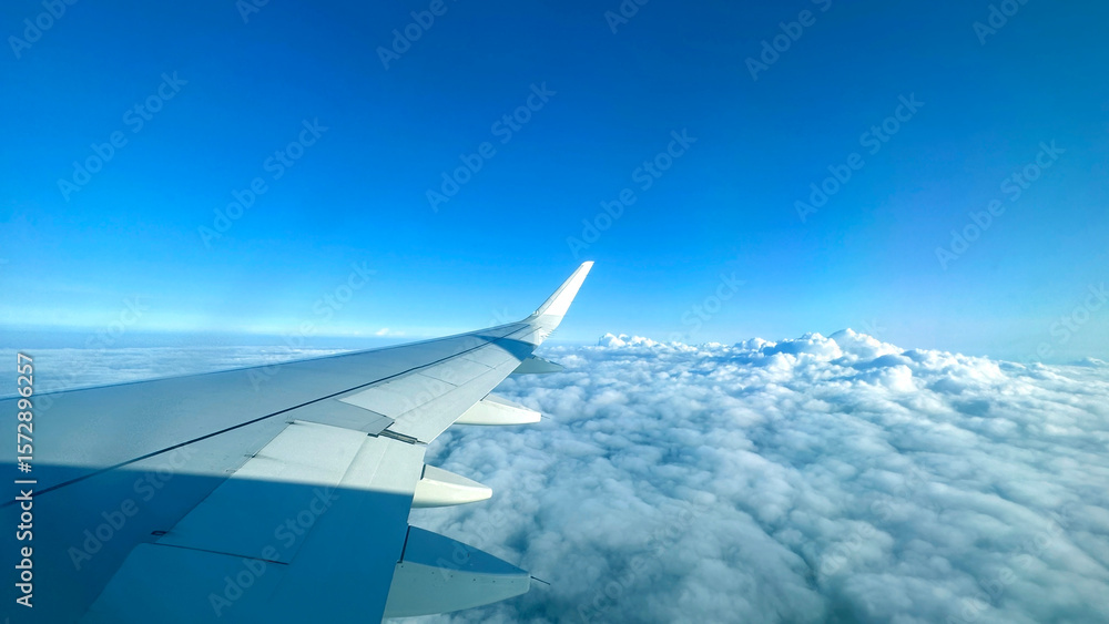 Obraz premium Airplane wing above clouds.View from airplane window a blue sky and clouds.