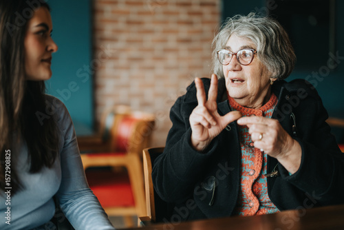 Foto An older woman in glasses converses expressively with a younger seated woman in a cozy indoor environment